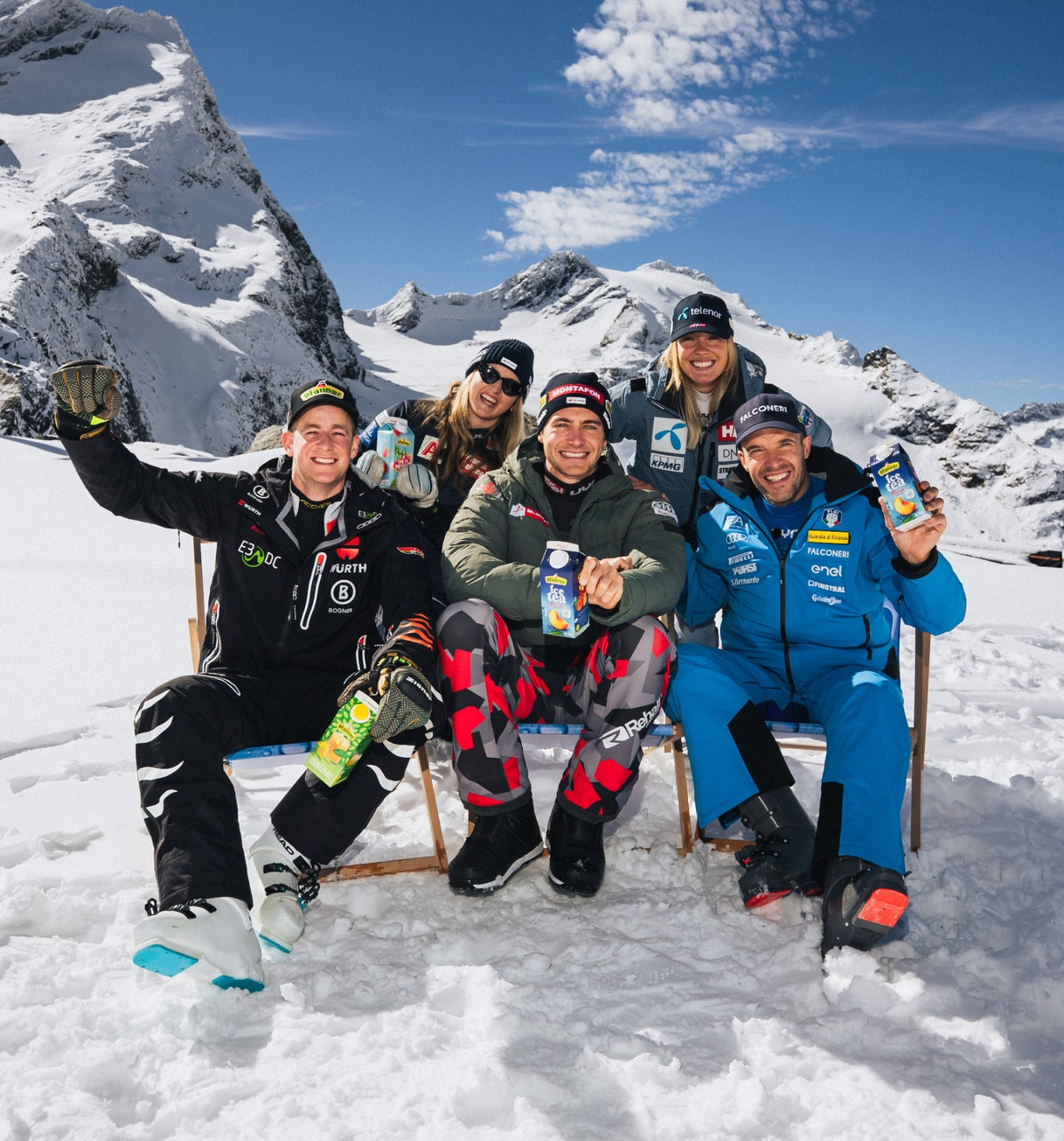 Pfanner Ice Tea Pfirsich Karton in den Händen einer Wintersportgruppe vor Berggipfeln