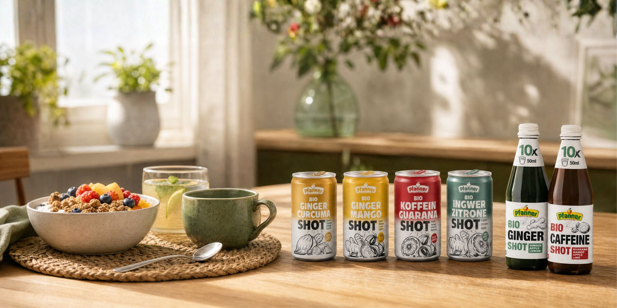 Pfanner Bio Ingwer Shots als Dosen und Flaschen auf einem Holztisch neben einer Frühstücksschale