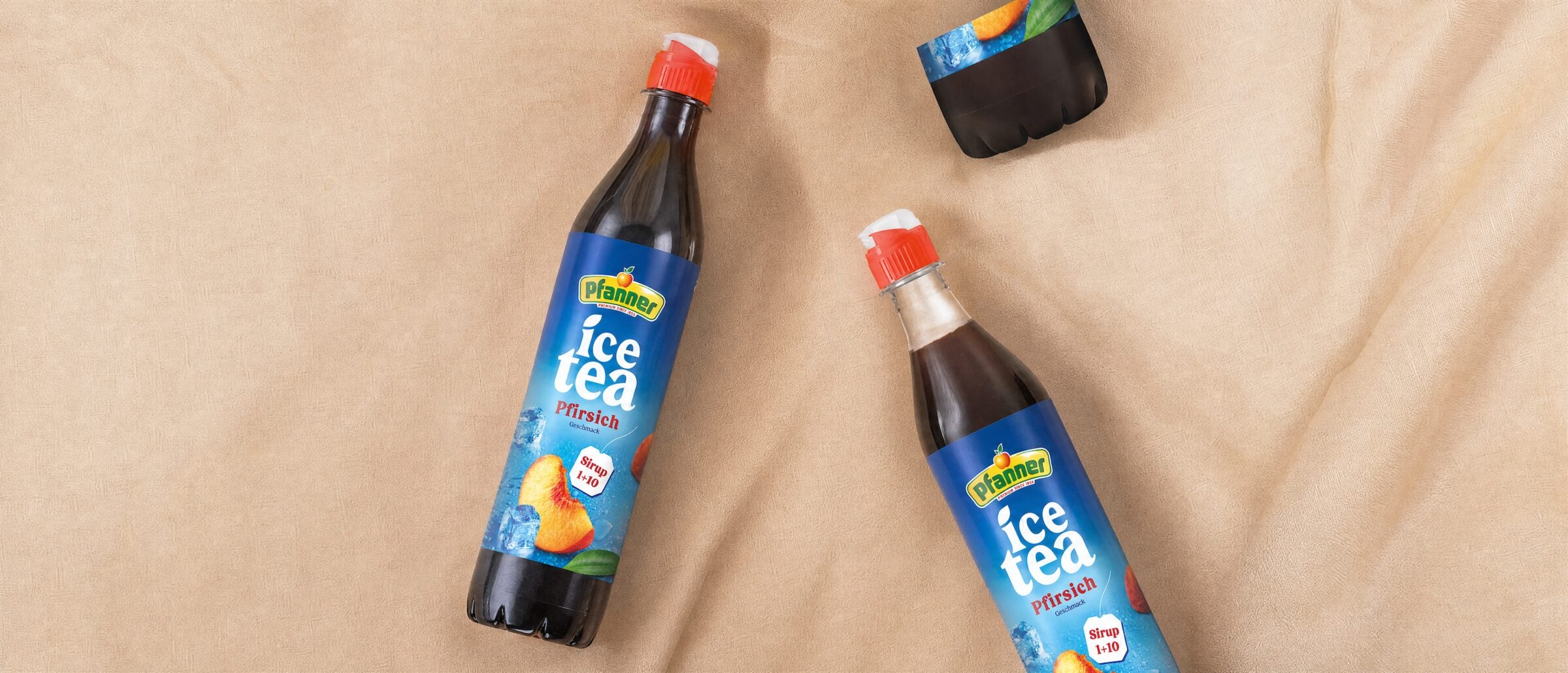 Zwei Flaschen Pfanner Ice Tea Sirup Pfirsich auf beigem Stoff